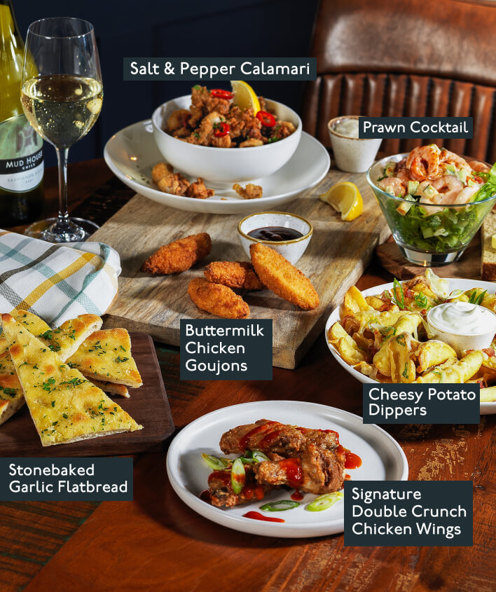 A table filled with Beefeater starters in dishes including chicken wings, calamari, garlic flatbread, potato dippers and a prawn cocktail.