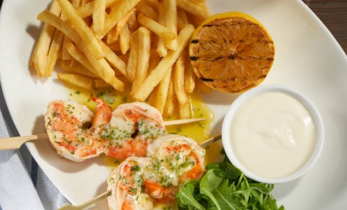 Beefeater menu item of Chargrilled King Prawns on skewers with French fries and white garlic mayonnaise in a pot.